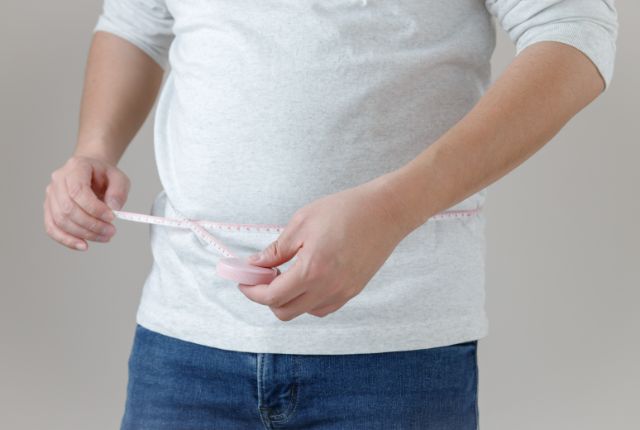 お腹にメジャーを巻いているふくよかな男性