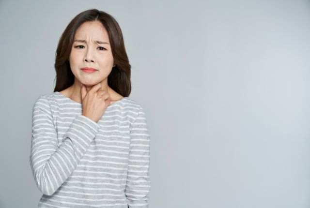 喉に違和感を覚えている女性